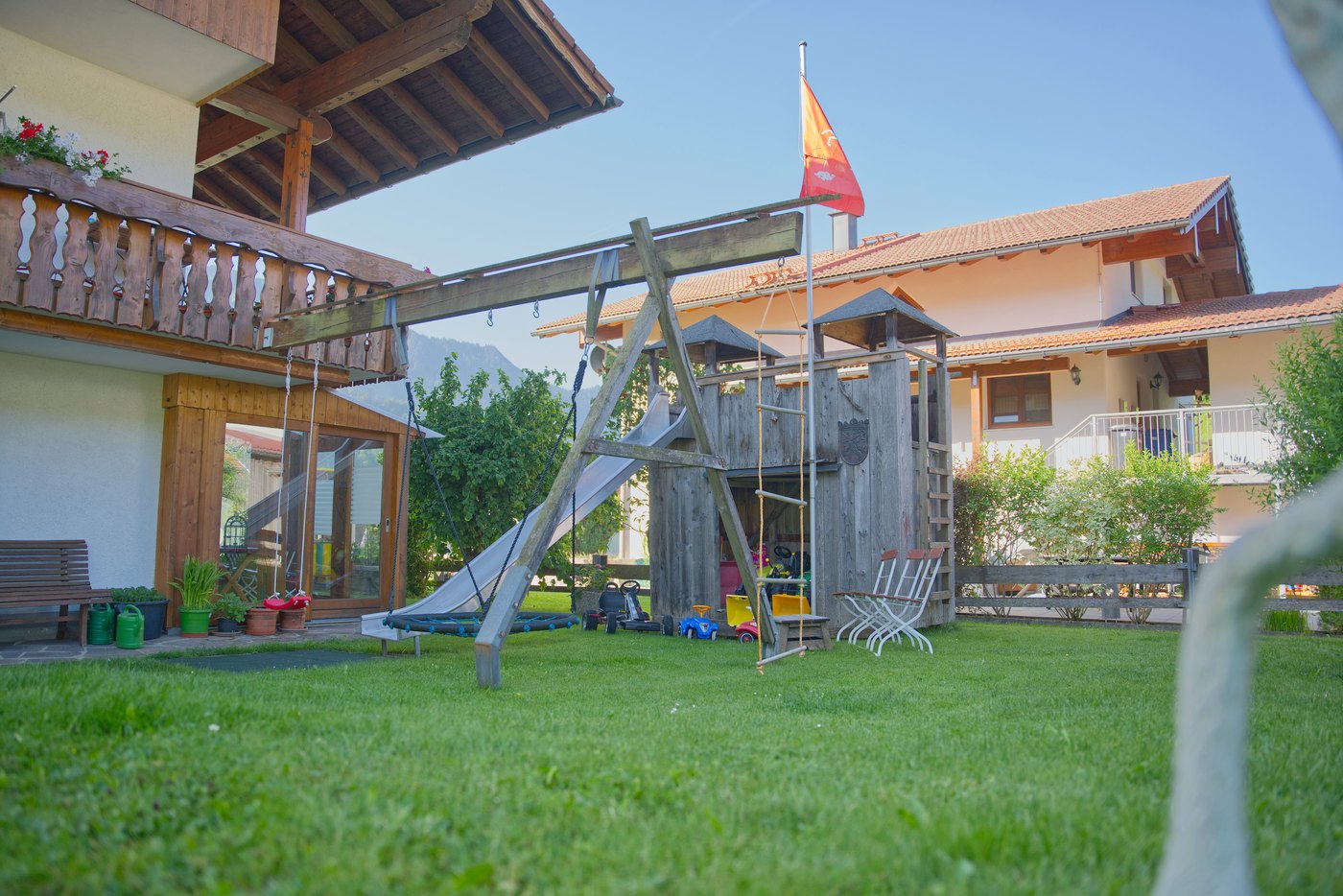 Blick über den Garten mit Ritterburg, Strickleiter und Spielfahrzeugen